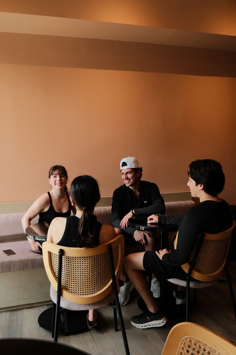 Cuatro personas conversando en el café de MUNA después de clase